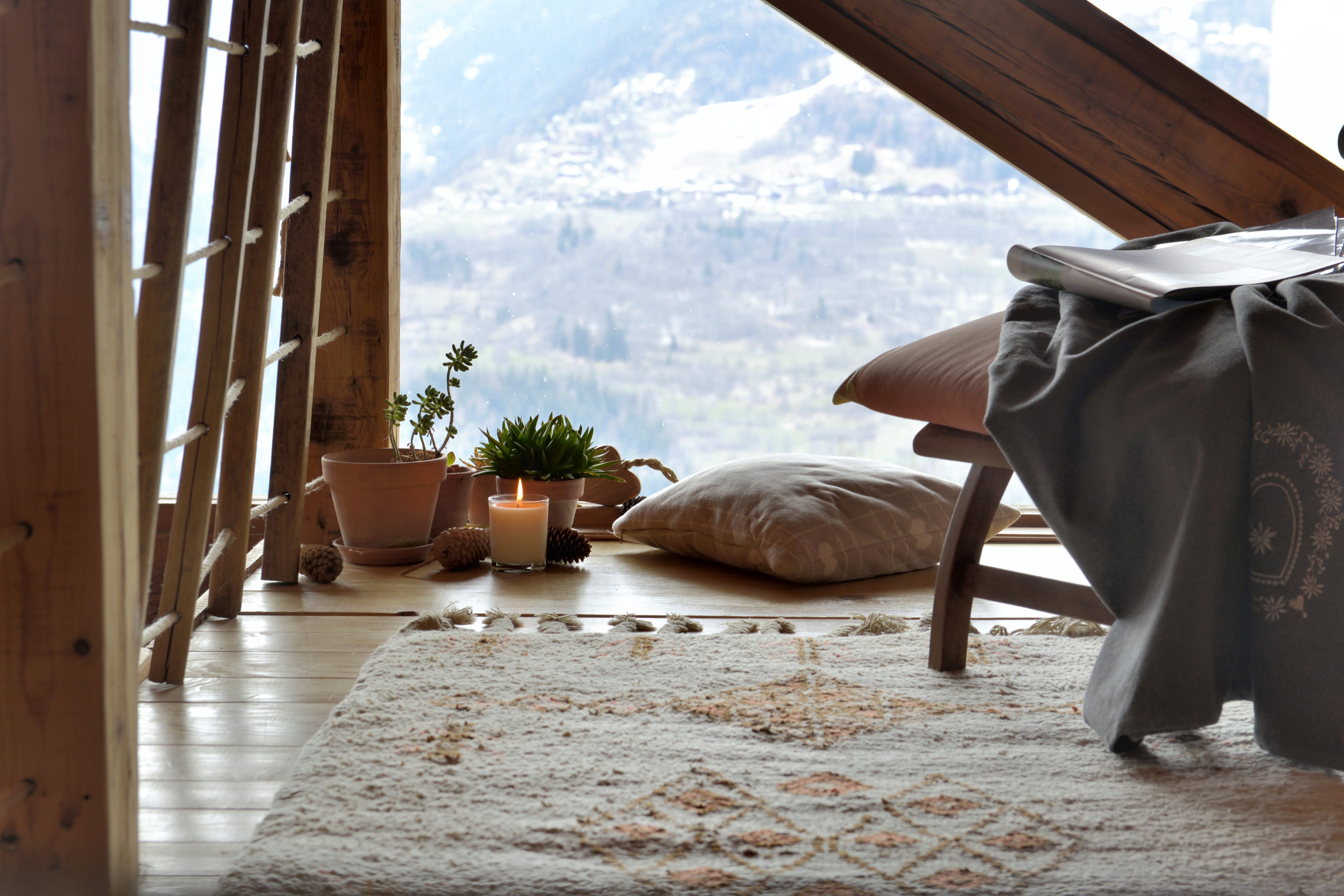 break room with chair, plants and  candle in front of paned glass in a cottage of mountain